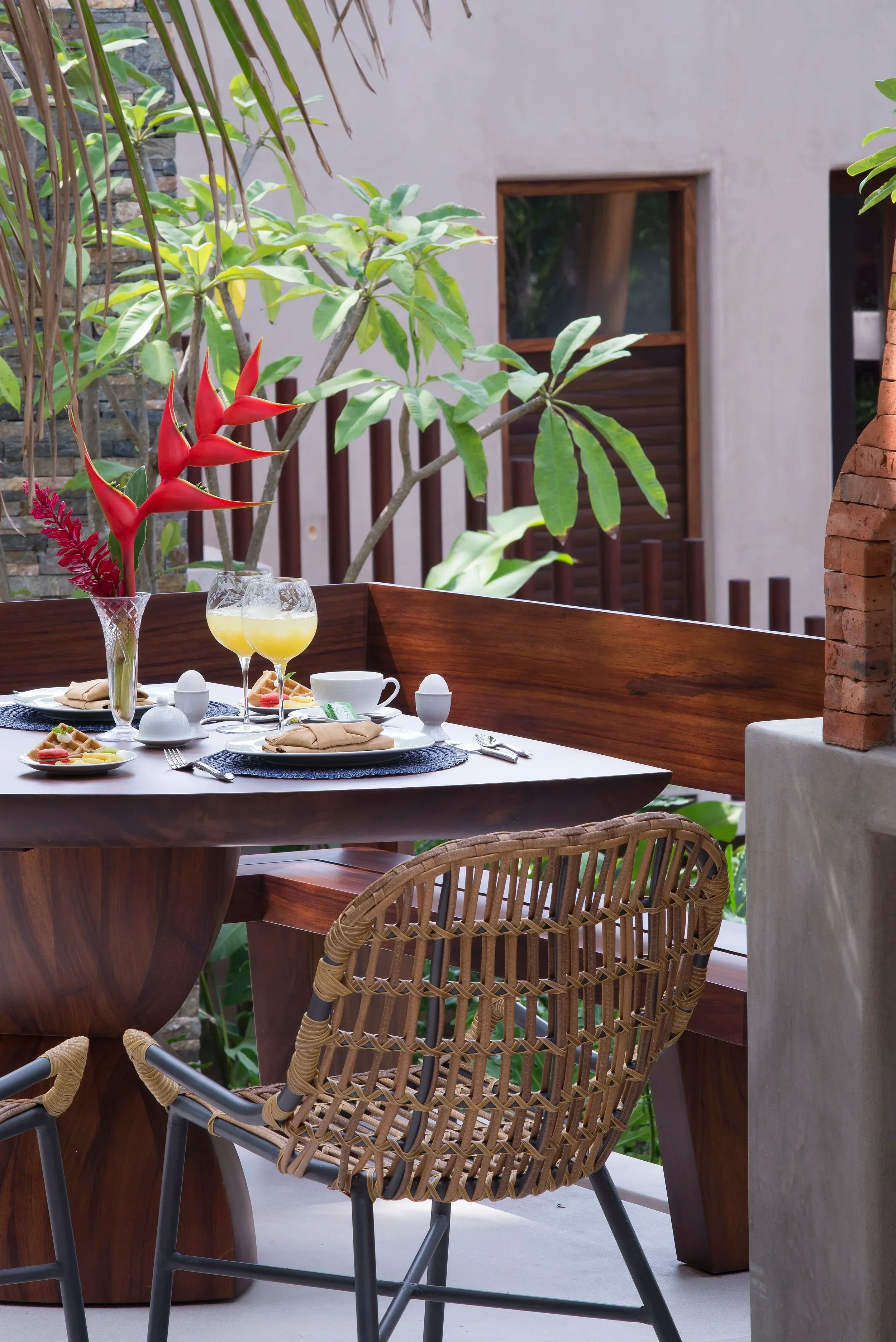 Breakfast table with fresh juice on a plant-filled terrace in the morning