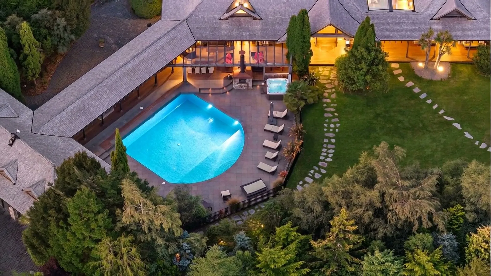 Dusk aerial of the lit pool and homestead — frame from the Verdan property film