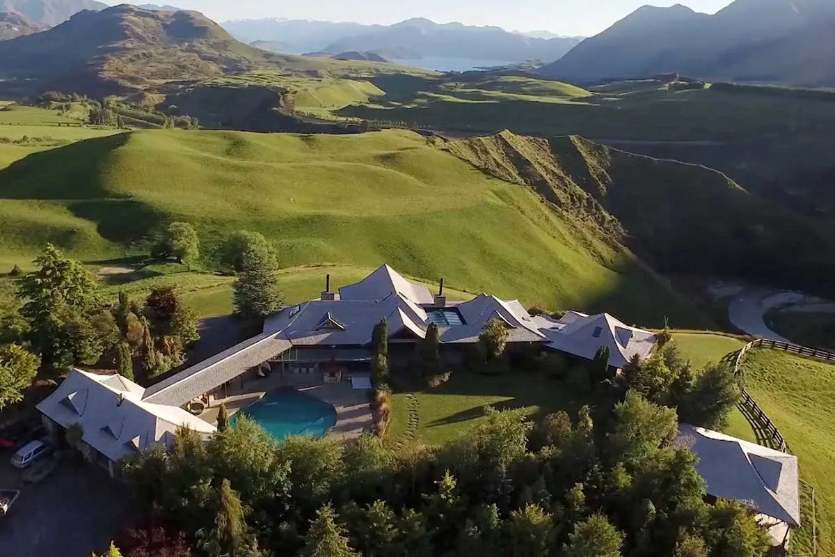 Aerial view of the Mahu Whenua homestead on a green ridge above the lake