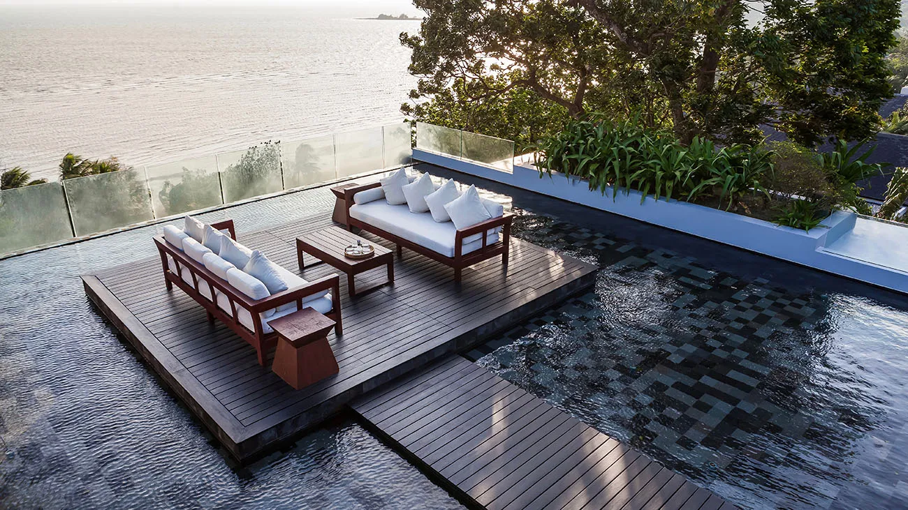 Secluded deck with sofas above the sea in late light